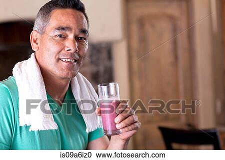 Stock Image - Man drinking smoothie in kitchen. Fotosearch