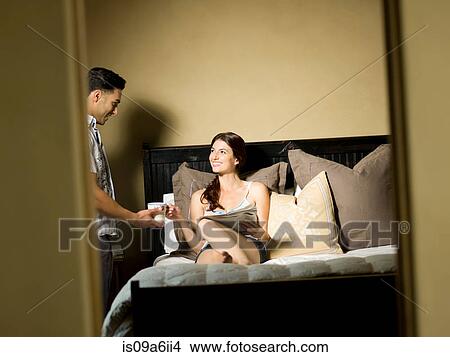 Man giving girlfriend cup of tea in bed View Large Photo Image Picture - Man giving girlfriend cup of tea in bed. Fotosearch