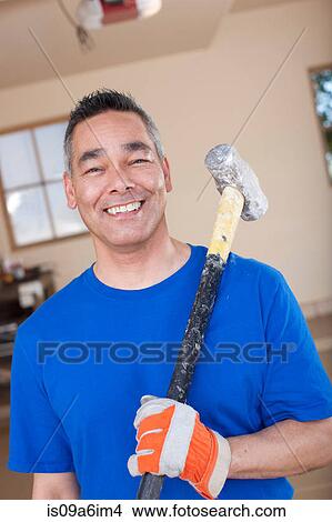 Man holding sledge hammer in garage View Large Photo Image Picture - Man holding sledge hammer in garage. Fotosearch