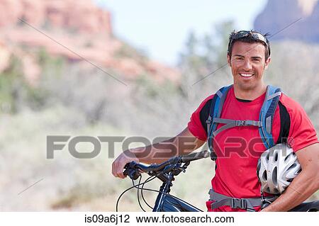 Stock Image - Man pushing mountain bike. Fotosearch