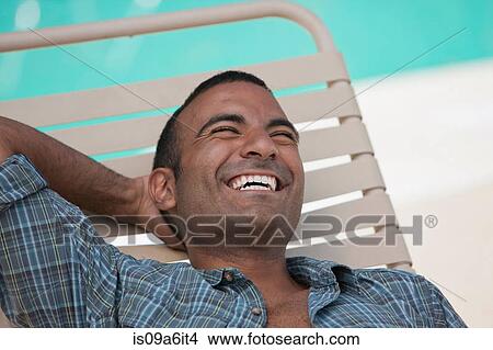 Picture - Man relaxing in lawn chair by pool. Fotosearch