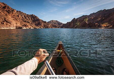 Stock Photograph - Man rowing canoe on still rural lake. Fotosearch