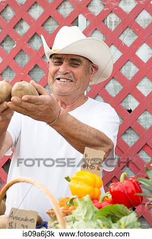 Stock Image - Man selling potatoes at farmer's market. Fotosearch
