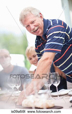 Stock Image - Man setting table outdoors. Fotosearch