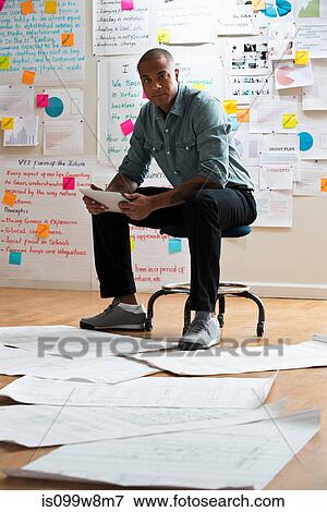 Man sitting on stool with digital tablet View Large Photo Image Stock Photo - Man sitting on stool with digital tablet. Fotosearch