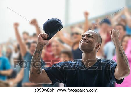 Stock Image - Man sports game, holding baseball cap and looking frustrated. Fotosearch
