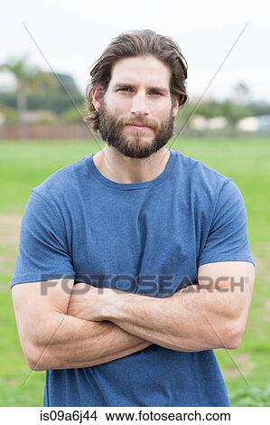 Picture - Man standing with arms crossed outdoors. Fotosearch
