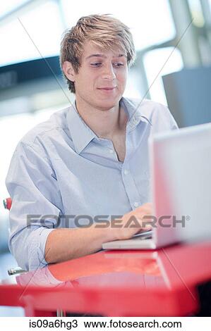 Stock Image - Man using laptop at desk. Fotosearch