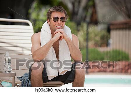 Stock Image - Man wearing towel by swimming pool. Fotosearch