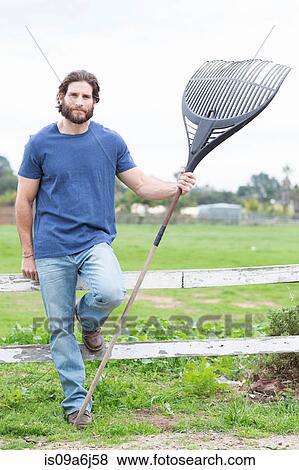 Man with hoe on wooden fence View Large Photo Image Stock Photo - Man with hoe on wooden fence. Fotosearch