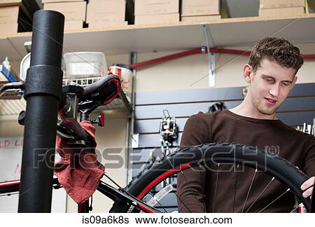 Stock Photograph - Mechanic working in bicycle repair shop. Fotosearch