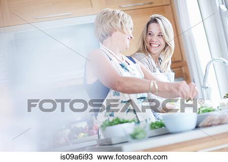 Stock Image - Mother and daughter cooking in kitchen. Fotosearch