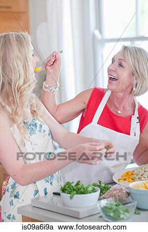 Stock Image - Mother and daughter cooking in kitchen. Fotosearch