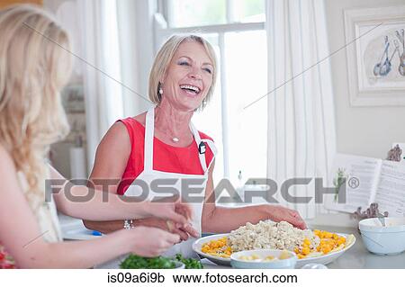 Stock Image - Mother and daughter cooking in kitchen. Fotosearch