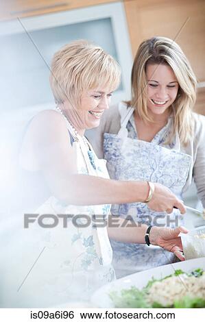 Stock Photograph - Mother and daughter cooking in kitchen. Fotosearch