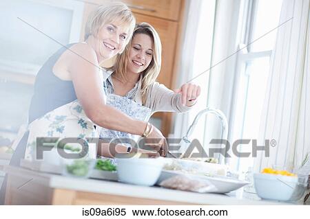 Stock Photography - Mother and daughter cooking in kitchen. Fotosearch