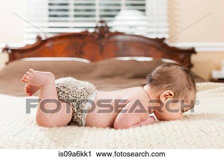 Stock Image - Newborn infant laying on bed. Fotosearch
