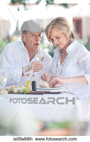 Stock Image - Older couple eating together outdoors. Fotosearch