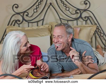 Picture - Older couple reading on bed. Fotosearch