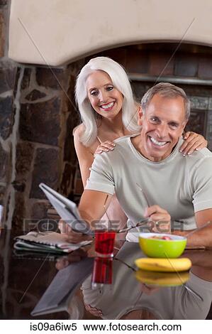 Stock Photography - Older couple smiling at breakfast. Fotosearch
