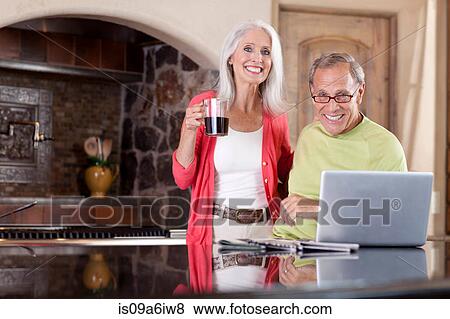 Stock Photo - Older couple using laptop at breakfast. Fotosearch