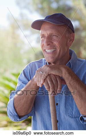 Stock Image - Older man gardening outdoors. Fotosearch