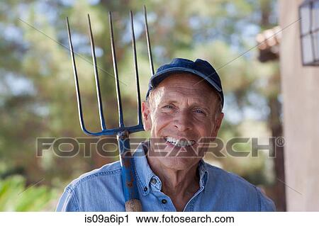 Stock Image - Older man gardening outdoors. Fotosearch