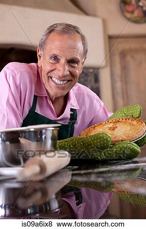Stock Photo - Older man holding pie in kitchen. Fotosearch