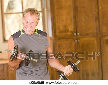 Older man lifting weights at home View Large Photo Image Stock Photograph - Older man lifting weights at home. Fotosearch