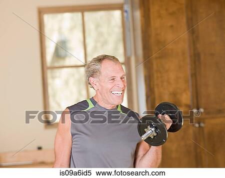 Stock Photography - Older man lifting weights at home. Fotosearch