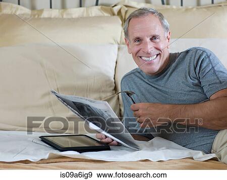 Older man reading newspaper on bed View Large Photo Image Stock Photo - Older man reading newspaper on bed. Fotosearch