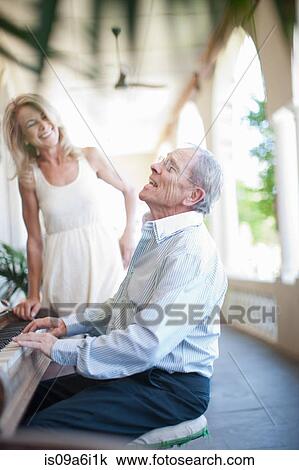 Stock Image - Older man singing at piano. Fotosearch