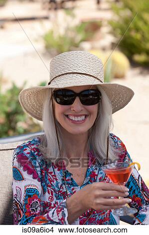 Picture - Older woman having cocktail outdoors. Fotosearch