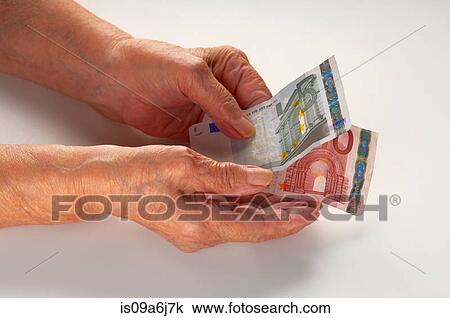 Stock Image - Older woman holding Euro notes. Fotosearch