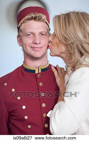 Stock Photo - Older woman kissing bellhop's cheek. Fotosearch
