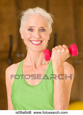 Stock Photo - Older woman lifting weights at home. Fotosearch