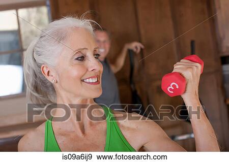 Stock Photo - Older woman lifting weights at home. Fotosearch