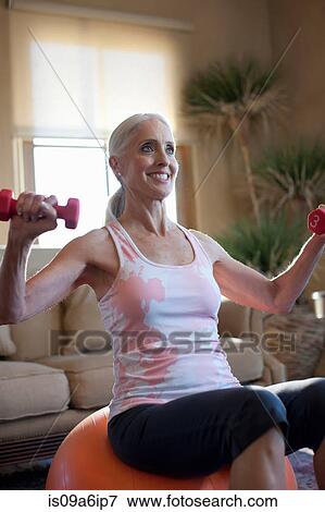 Older woman lifting weights at home View Large Photo Image Stock Photo - Older woman lifting weights at home. Fotosearch