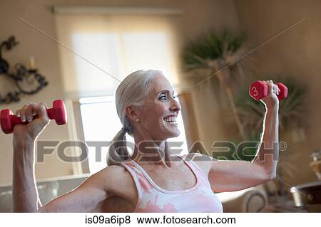 Older woman lifting weights at home View Large Photo Image Stock Photo - Older woman lifting weights at home. Fotosearch