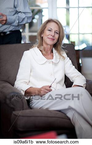 Stock Image - Older woman relaxing in armchair. Fotosearch