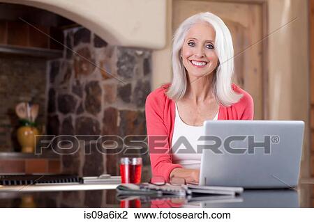 Older woman using laptop at breakfast View Large Photo Image Stock Image - Older woman using laptop at breakfast. Fotosearch
