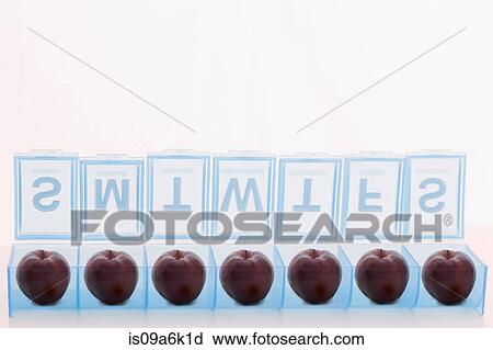 Stock Image - Pill holder containing apples. Fotosearch