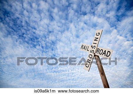 Picture - 'Railroad crossing' sign under blue sky. Fotosearch