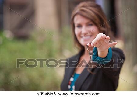 Stock Photography - Realtor holding keys outside house. Fotosearch
