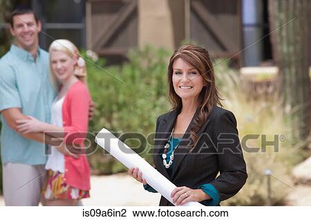 Stock Image - Realtor with couple outside home. Fotosearch