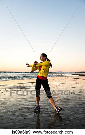 Stock Photo - Runner stretching on beach. Fotosearch