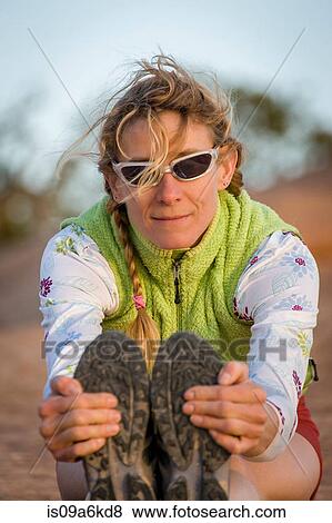 Stock Photo - Runner stretching on dirt road. Fotosearch