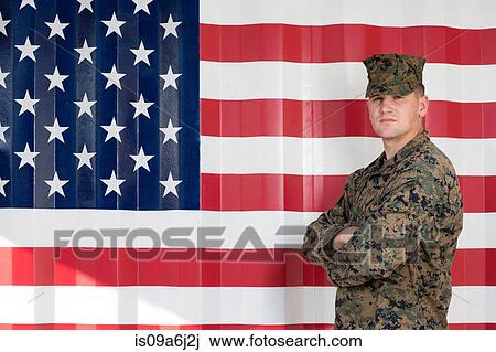 Stock Image - Serviceman in camouflage by US flag. Fotosearch