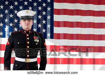 Picture - Serviceman in dress blues by US flag. Fotosearch