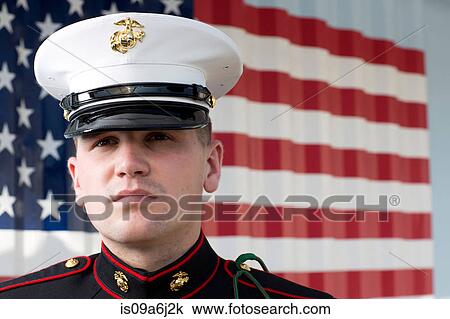 Stock Image - Serviceman in dress blues by US flag. Fotosearch